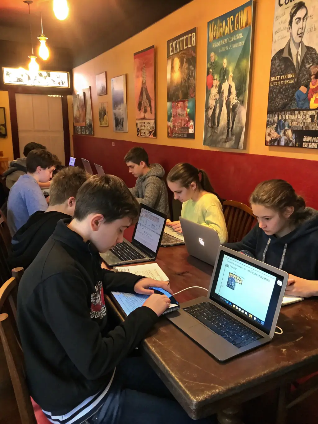 A photograph of teenagers participating in a creative writing workshop, with laptops and notebooks spread out on tables, and an instructor guiding them through the writing process.
