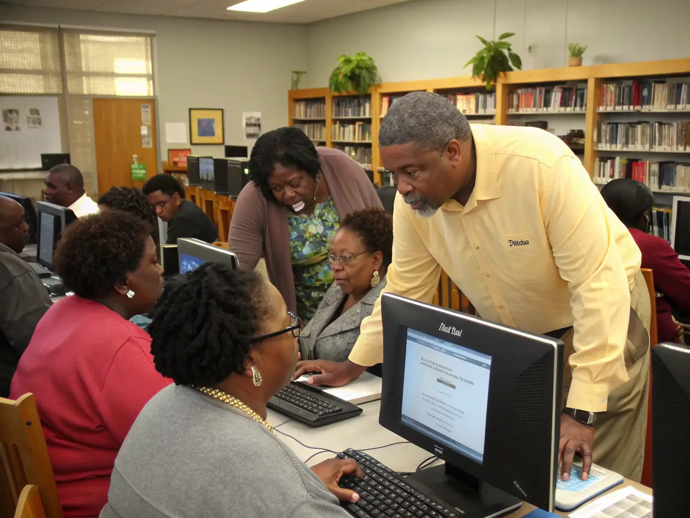 An image showing a diverse group of adults attending a computer literacy workshop at the library. The participants are engaged and focused, highlighting the library's role in providing essential digital skills training.